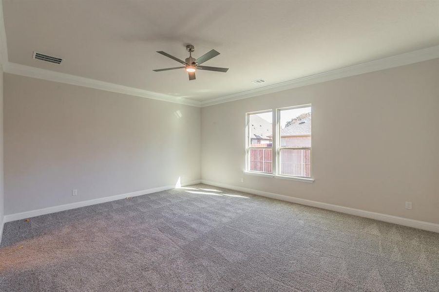 Carpeted spare room featuring ceiling fan and crown molding