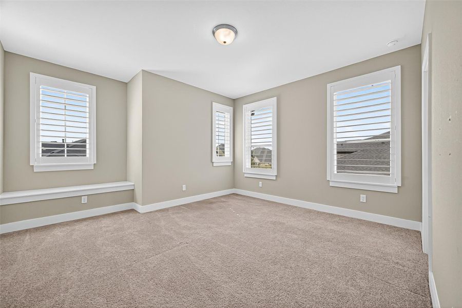 Secondary bedroom 2 upstairs with plantation shutters and window seat.