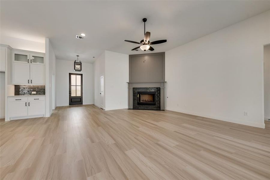 Unfurnished living room featuring ceiling fan and light hardwood / wood-style flooring