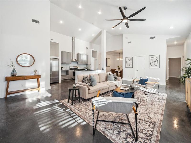 Living room with high vaulted ceiling and ceiling fan with notable chandelier