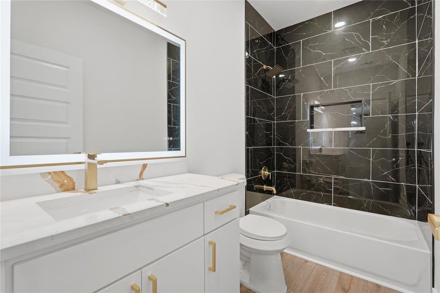 Modern bathroom featuring a white vanity with gold-tone hardware, a rectangular undermount sink, and a gold-tone faucet