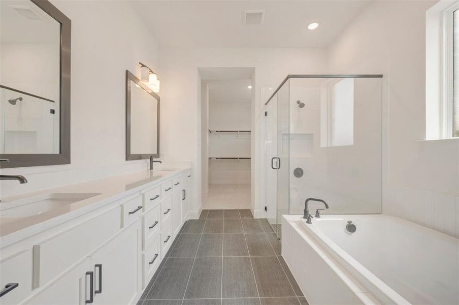 Contemporary bathroom featuring a double vanity with stone countertops, a freestanding bathtub, and a glass-enclosed shower