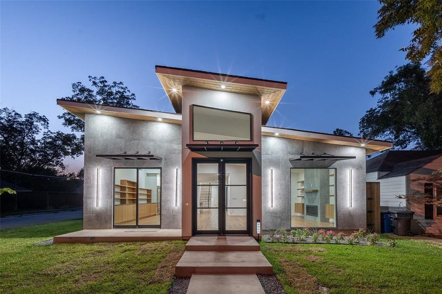 Exterior entry at dusk featuring french doors and a lawn