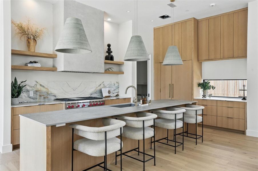 Kitchen featuring open shelves, modern cabinets, light wood-style flooring, a breakfast bar, and light countertops Kitchen featuring open shelves, modern cabinets, light wood-style flooring, a breakfast bar, and light countertops