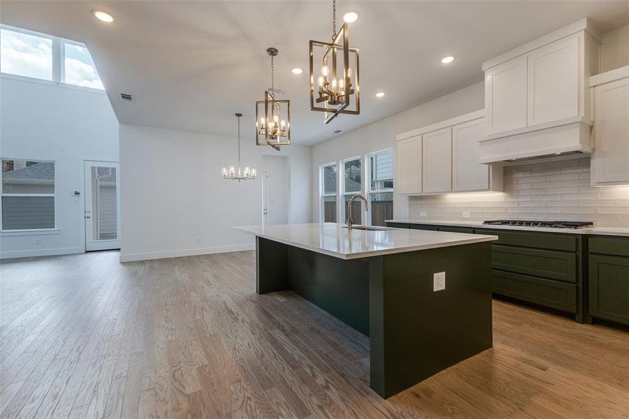 Kitchen featuring sink, an island with sink, light hardwood / wood-style flooring, and tasteful backsplash