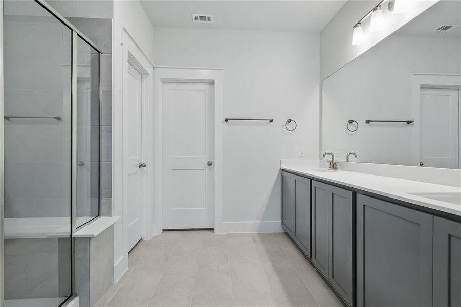 Full bath with double vanity and a shower stall