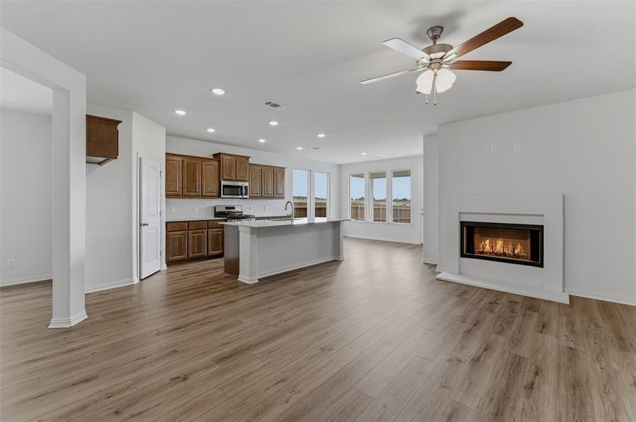 Open-concept living area with wood-finish flooring, a contemporary fireplace, and recessed lighting