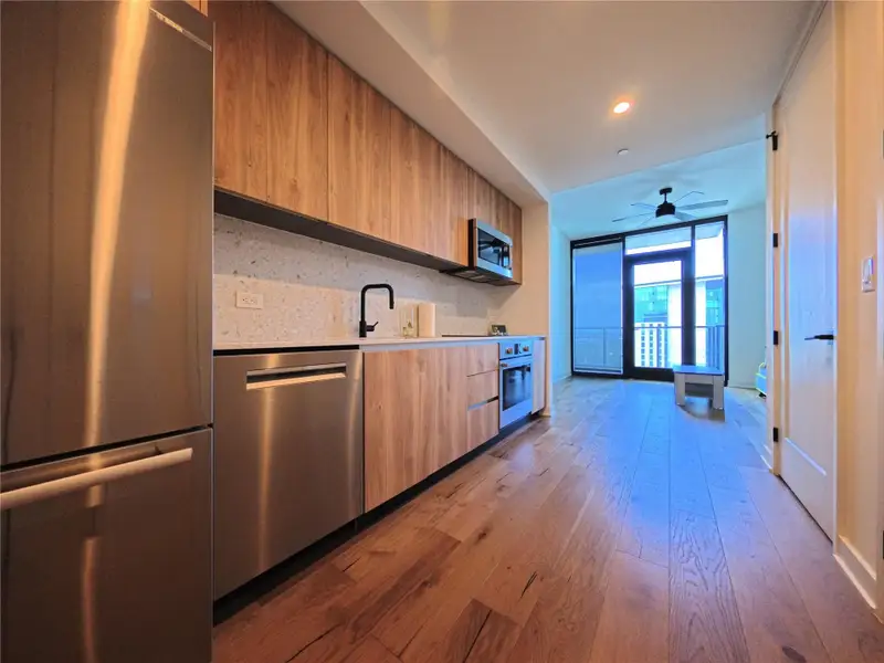 Kitchen with modern cabinets, appliances with stainless steel finishes, light countertops, wood-type flooring, and light brown cabinets Kitchen with modern cabinets, appliances with stainless steel finishes, light countertops, wood-type flooring, and light brown cabinets