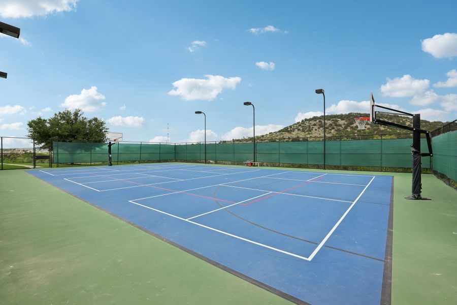 The property features a multi-sport court with blue and green surfacing, equipped with basketball hoops and perimeter lighting