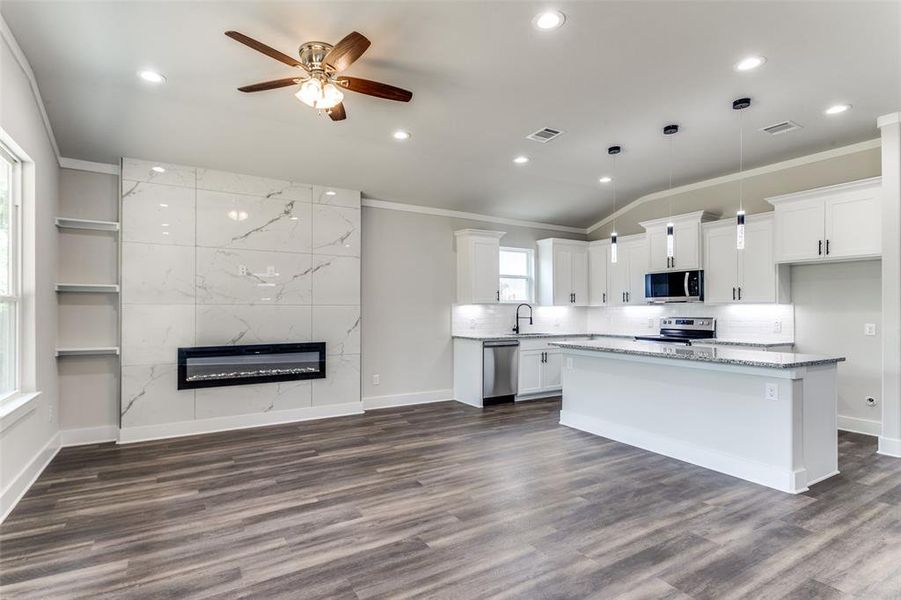 Kitchen featuring white cabinetry, crown molding, appliances with stainless steel finishes, and a high end fireplace