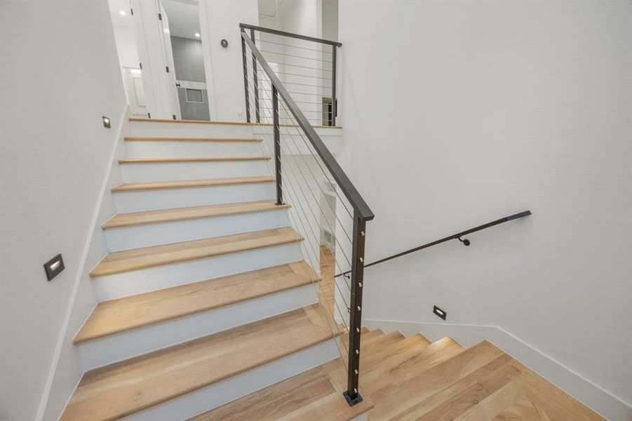 The natural hardwood staircase, complemented by industrial-inspired handrails and integrated floor lighting for nighttime safety, creates a distinctive architectural feature that adds both style and functionality to the home’s overall design. The natural hardwood staircase, complemented by industrial-inspired handrails and integrated floor lighting for nighttime safety, creates a distinctive architectural feature that adds both style and functionality to the home’s overall design.