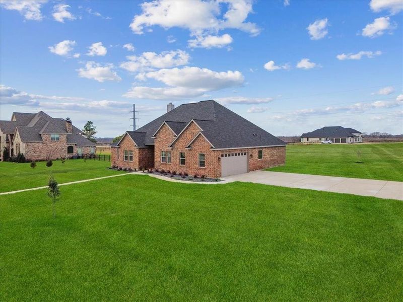 View of front of property with brick siding, driveway, an attached garage, and a front lawn