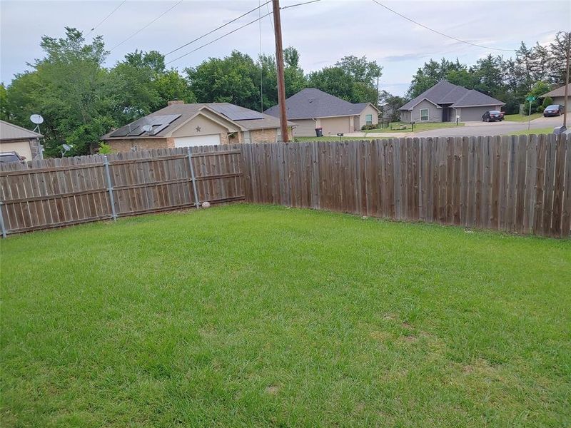 Expansive backyard featuring a lush green lawn, full wood privacy fencing, and mature perimeter trees