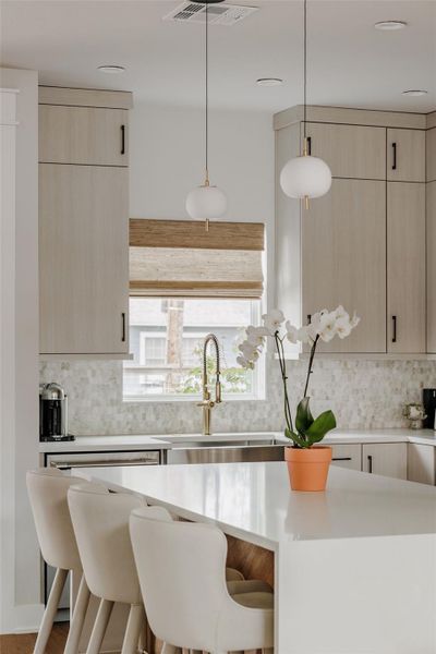 Kitchen featuring a kitchen breakfast bar, pendant lighting, light wood finish cabinets, and light stone countertops