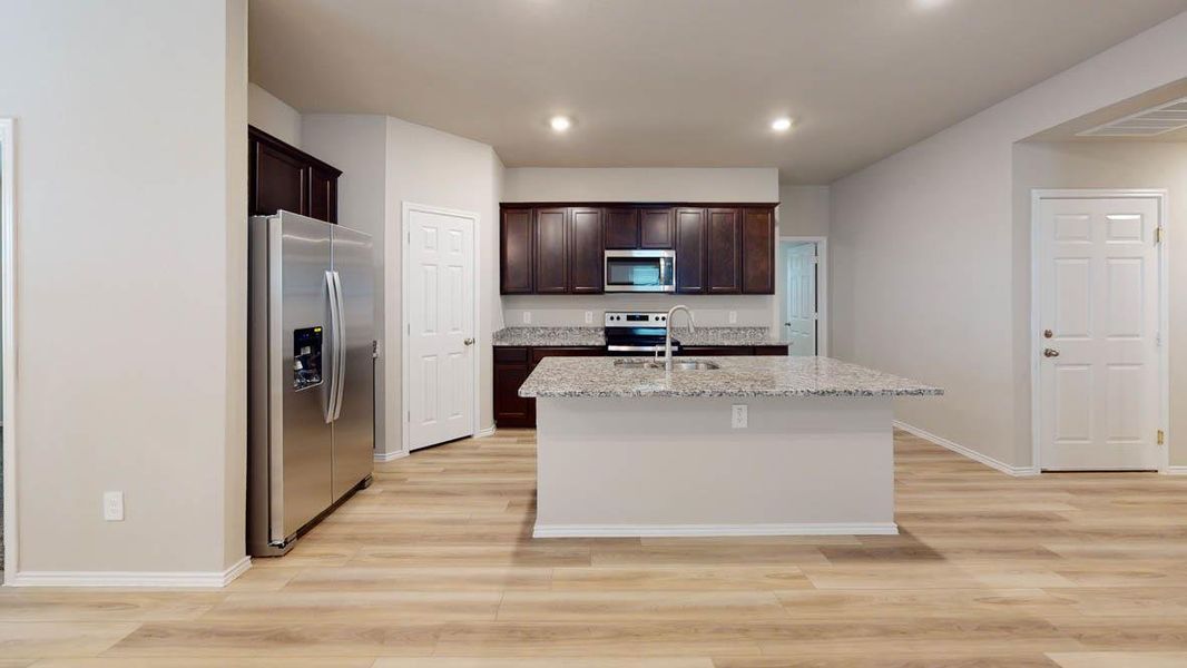 A well-appointed kitchen features a central island, granite counters, and integrated stainless steel appliances. A well-appointed kitchen features a central island, granite counters, and integrated stainless steel appliances.