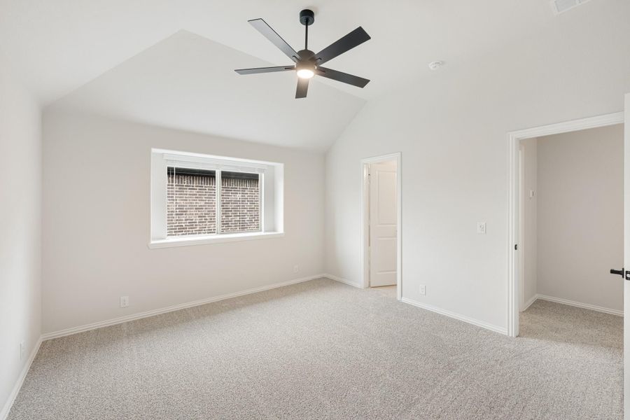 Empty bedroom with vaulted ceiling, black ceiling fan, carpet flooring, and two doorways Empty bedroom with vaulted ceiling, black ceiling fan, carpet flooring, and two doorways