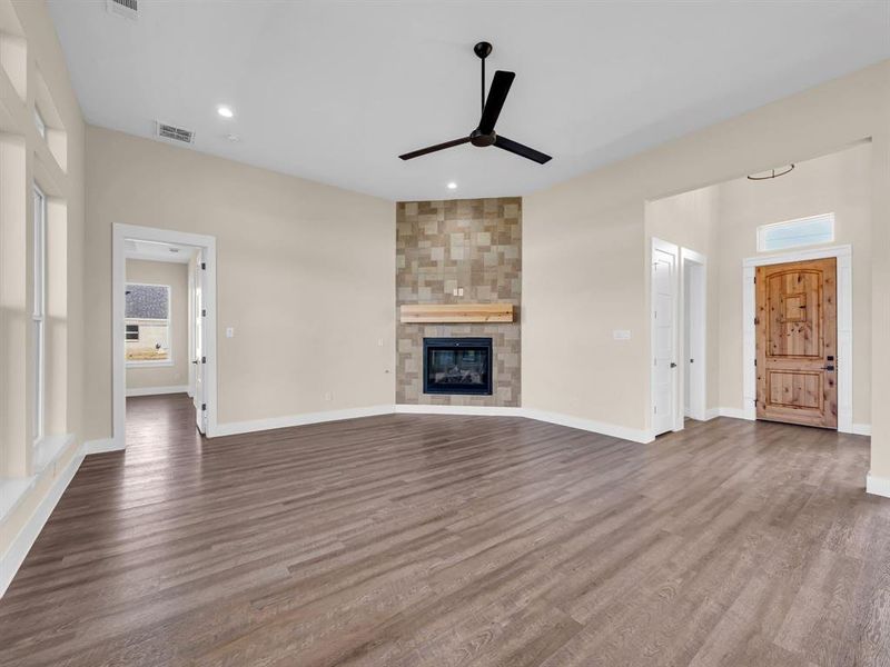 Unfurnished living room with wood-type flooring, a fireplace, and ceiling fan