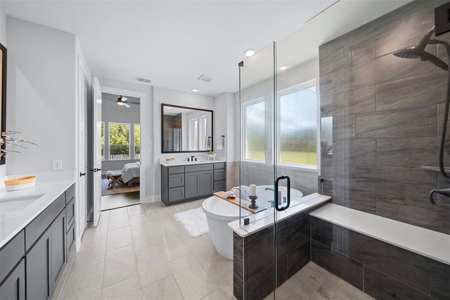 Bathroom with two vanities, a shower stall, ensuite bath, ceiling fan, and a freestanding bath