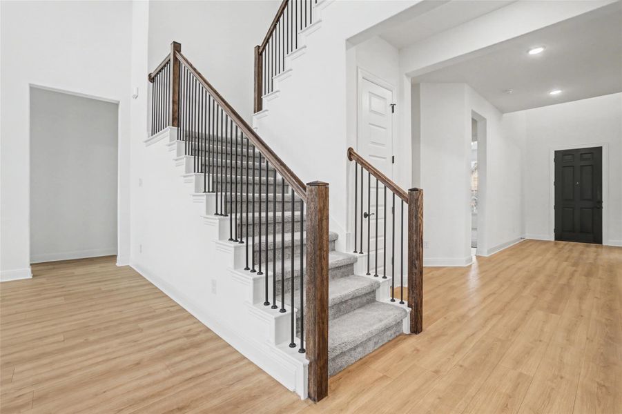 Stairway with wood finished floors, recessed lighting, and a high ceiling