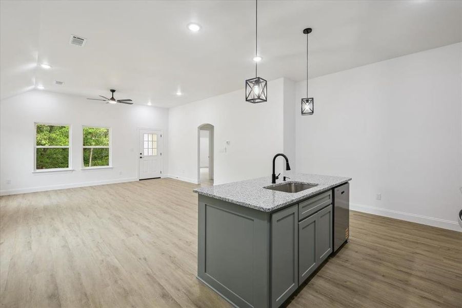 Kitchen featuring gray cabinets, arched walkways, pendant lighting, light stone counters, and light wood-type flooring Kitchen featuring gray cabinets, arched walkways, pendant lighting, light stone counters, and light wood-type flooring