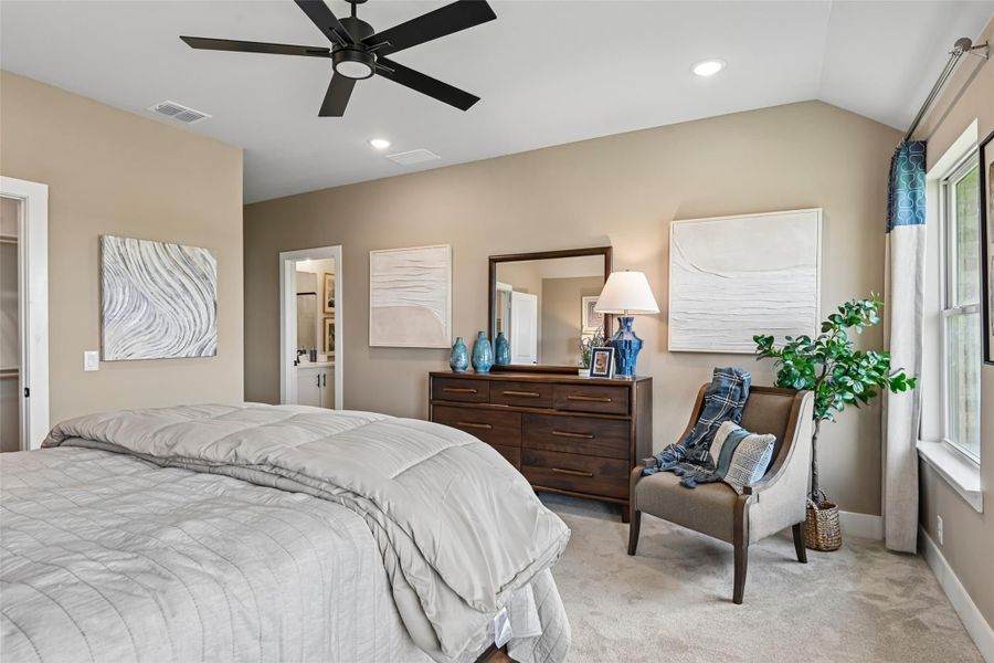 Bedroom with vaulted ceiling, ceiling fan, wood dresser, and ensuite bathroom doorway Bedroom with vaulted ceiling, ceiling fan, wood dresser, and ensuite bathroom doorway