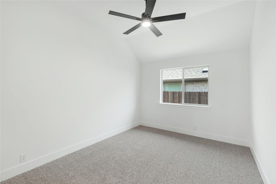 Empty bedroom with vaulted ceiling, ceiling fan, carpet flooring, and single window