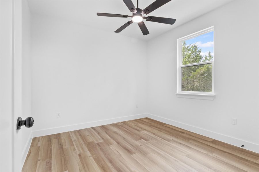 Secondary bedroom with light wood-type flooring and a ceiling fan