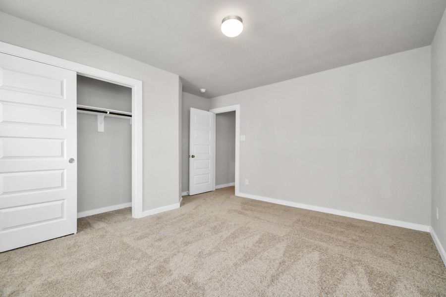 generously sized secondary bedrooms, showcasing 5-panel doors with modern hardware, large windows adorned with privacy blinds, and spacious closets boasting sleek and contemporary finishes. Sample photo of completed home with similar floor plan. Actual colors and selections may vary.