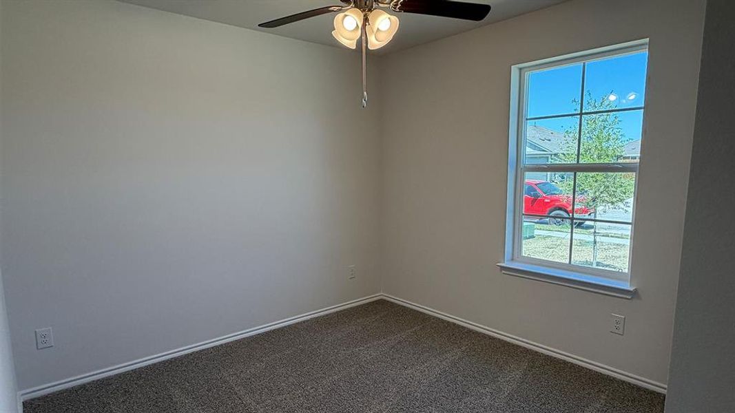 Empty room with a ceiling fan and dark carpet