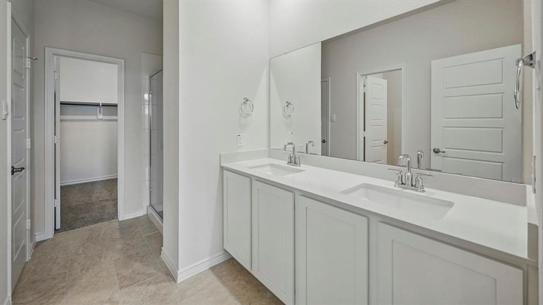 Dual vanity with white cabinetry, integrated sinks, chrome fixtures, and a full-width mirror