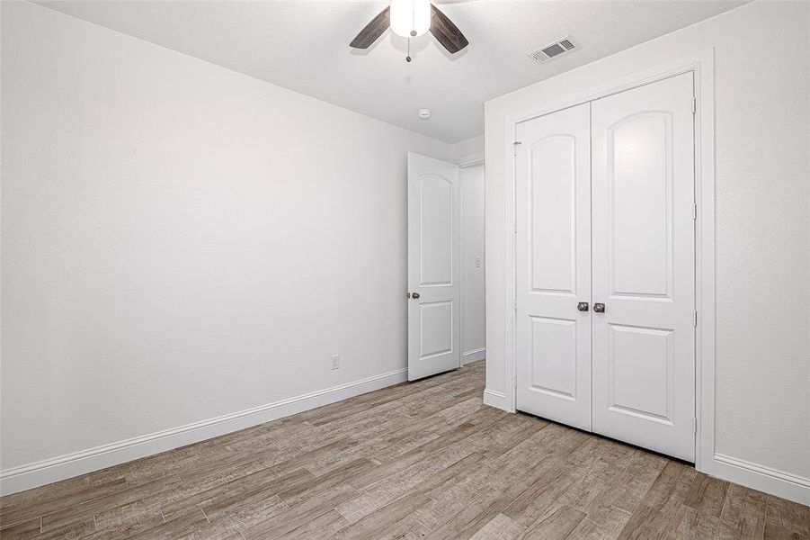 Unfurnished bedroom with light wood finished floors, a closet, baseboards, and a ceiling fan Unfurnished bedroom with light wood finished floors, a closet, baseboards, and a ceiling fan