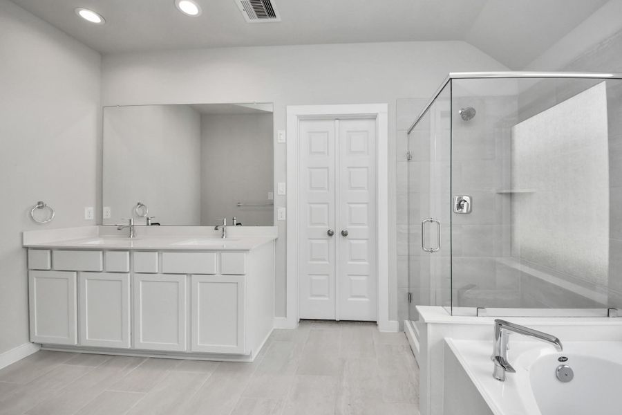 Elevate your daily routine at the elegant vanity, now equipped with double sinks, light countertops, modern hardware, and beautiful recessed lights. Sample photo of completed home with similar floor plan. Actual colors and selections may vary.