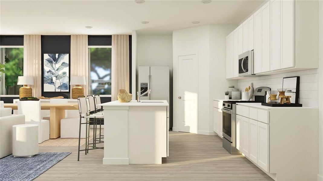 Kitchen featuring stainless steel appliances, a kitchen bar, a center island with sink, white cabinets, and light wood-type flooring