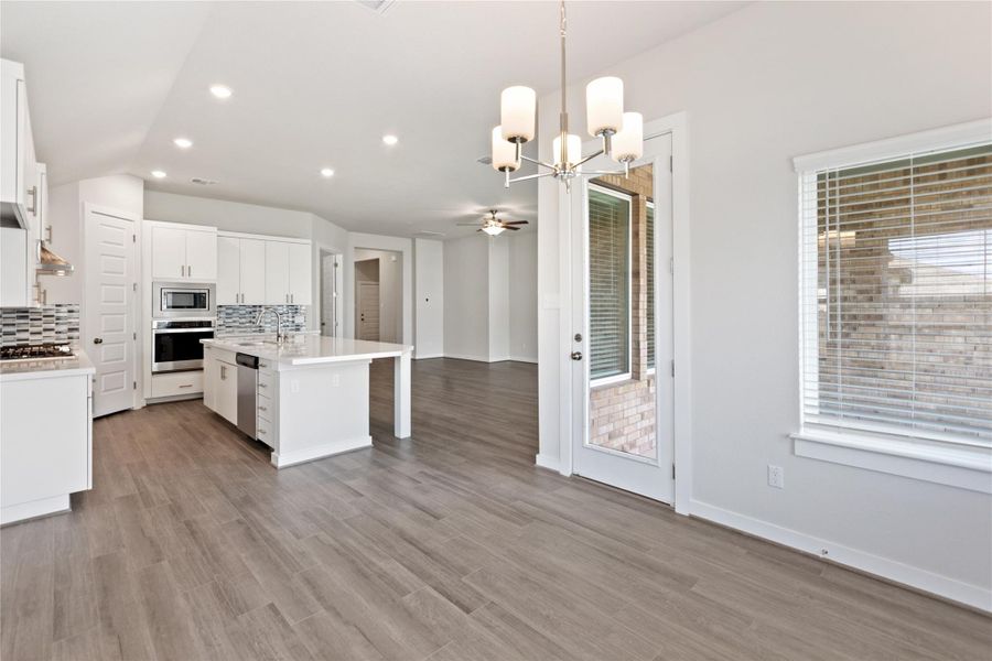Kitchen featuring white cabinets, decorative light fixtures, a chandelier, tasteful backsplash, and open floor plan