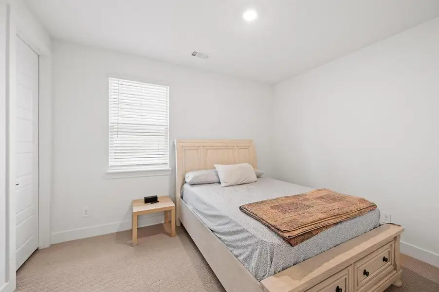 Carpeted bedroom featuring white walls, a single window with blinds, and a built-in closet with a white paneled door Carpeted bedroom featuring white walls, a single window with blinds, and a built-in closet with a white paneled door