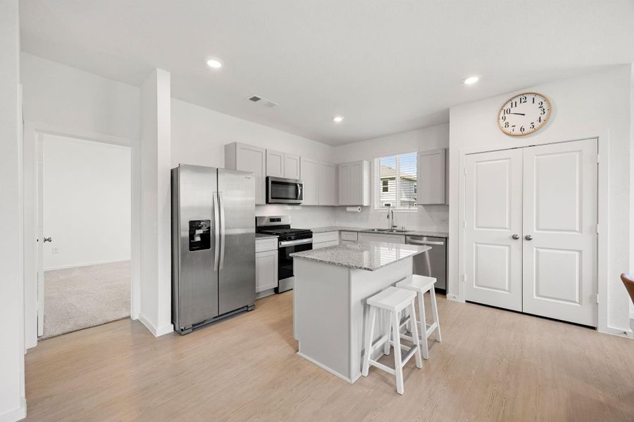 The heart of the home features a spacious kitchen with granite countertops, stainless steel appliances, ample cabinet storage, and a large center island ideal for meal prep and casual dining.