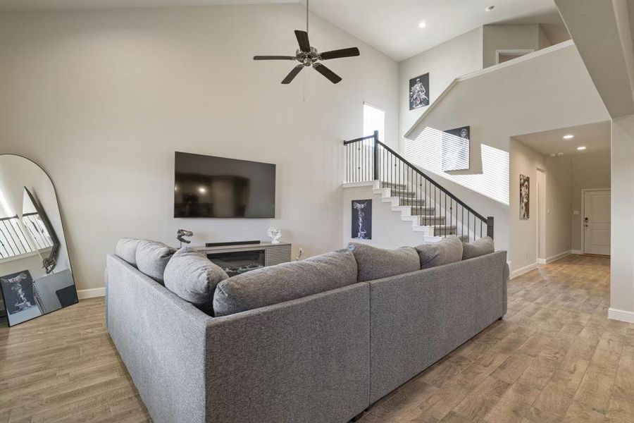 Living room featuring light wood-style floors, a ceiling fan, a fireplace, and vaulted ceiling Living room featuring light wood-style floors, a ceiling fan, a fireplace, and vaulted ceiling