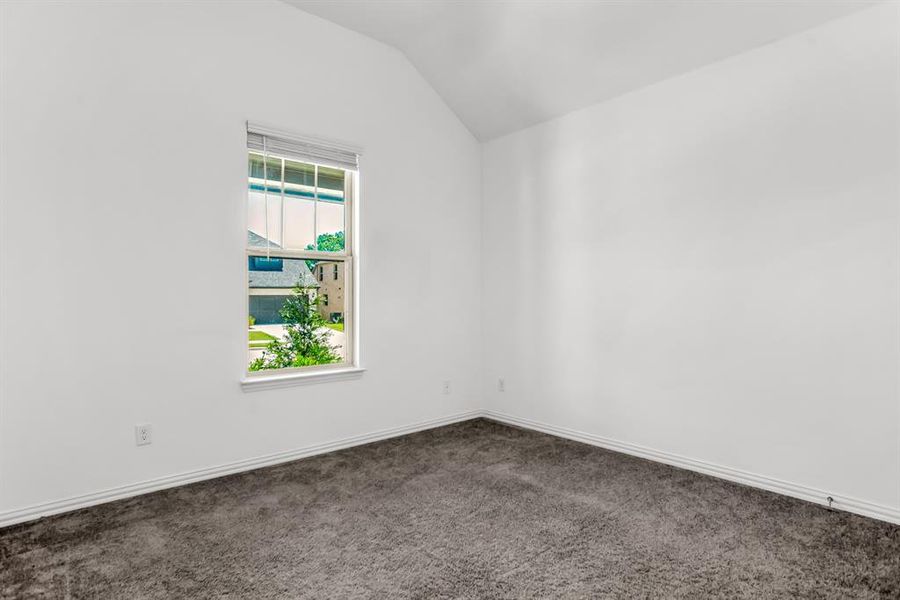 Carpeted room with a vaulted ceiling and a single window featuring blinds