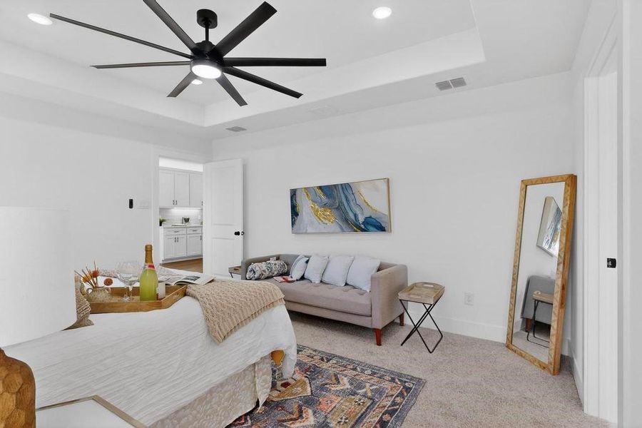 Primary bedroom with light carpet, recessed lighting, ceiling fan, and a tray ceiling Primary bedroom with light carpet, recessed lighting, ceiling fan, and a tray ceiling