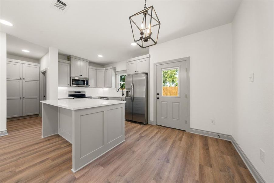 Kitchen with appliances with stainless steel finishes, hanging light fixtures, a kitchen island, a chandelier, and recessed lighting