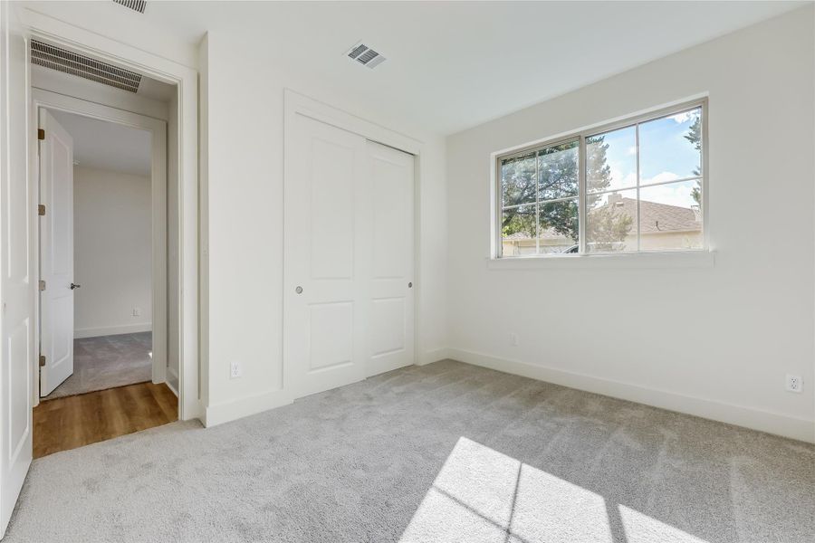 Unfurnished bedroom featuring light carpet and a closet Unfurnished bedroom featuring light carpet and a closet