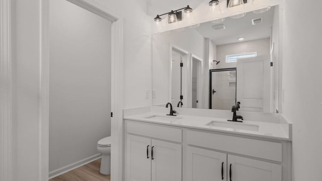 The spa-like primary bath features dual vanities and quartz countertops
