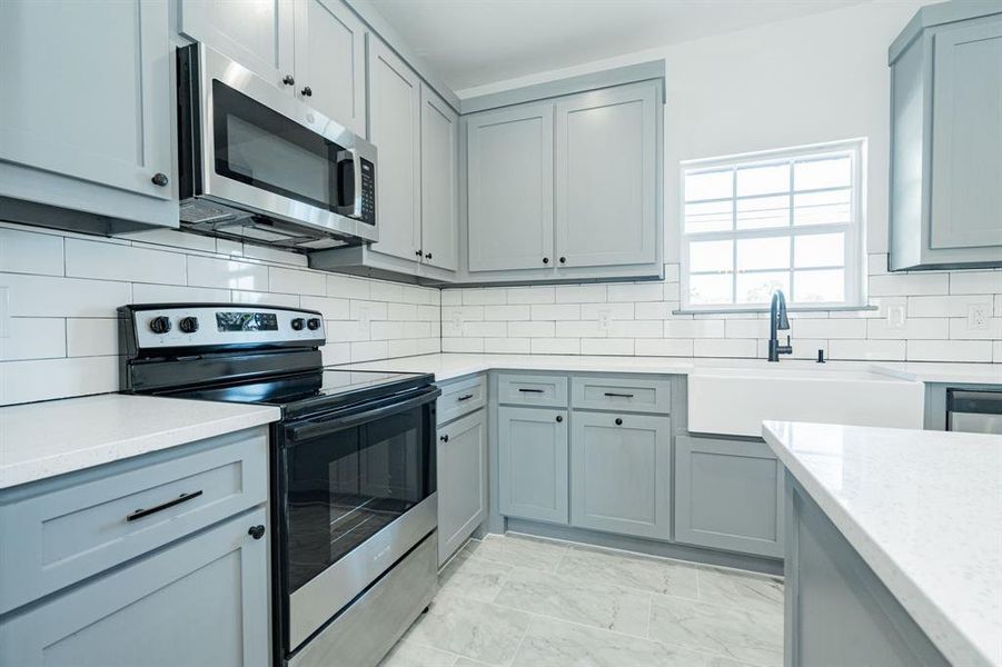 Kitchen with sink, light tile patterned floors, backsplash, and stainless steel appliances