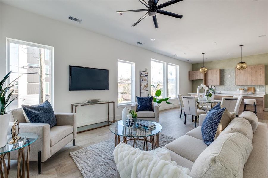 Living room featuring light wood-type flooring, a wealth of natural light, and ceiling fan