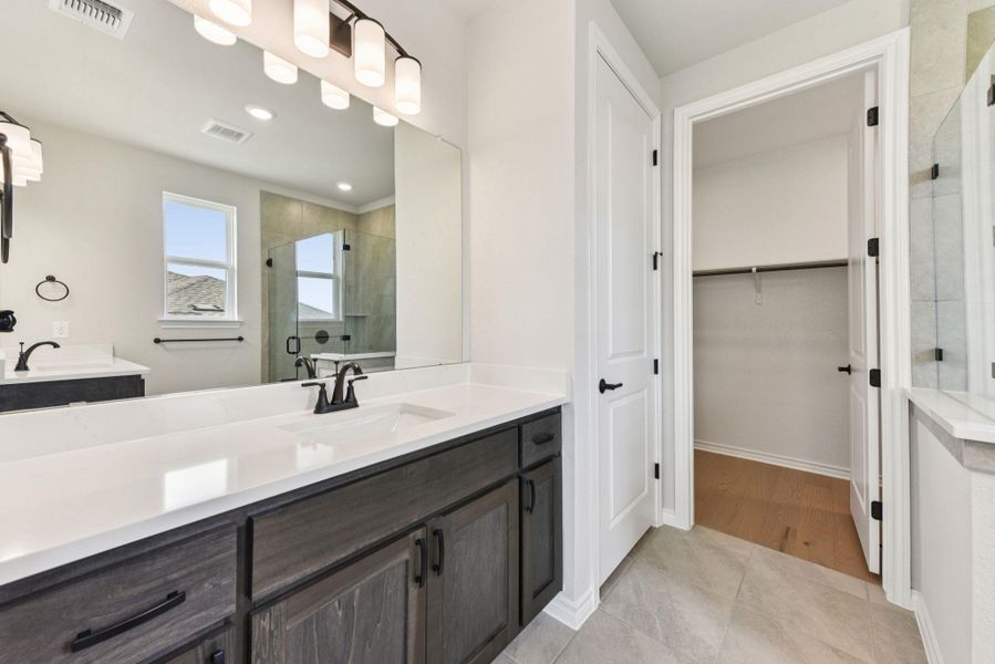 Bathroom featuring a stall shower, vanity, light tile patterned flooring, a walk in closet, and recessed lighting