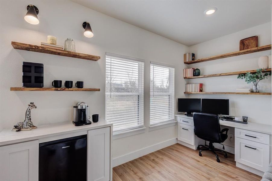 Office area with built in desk and light hardwood / wood-style flooring Office area with built in desk and light hardwood / wood-style flooring