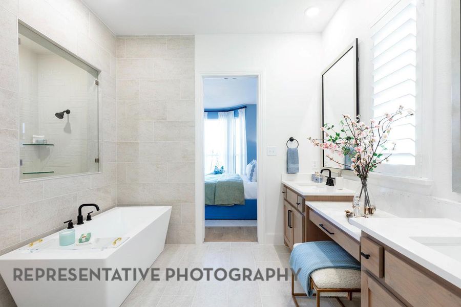 Ensuite bathroom featuring a freestanding tub, two vanities, and tile patterned floors Ensuite bathroom featuring a freestanding tub, two vanities, and tile patterned floors