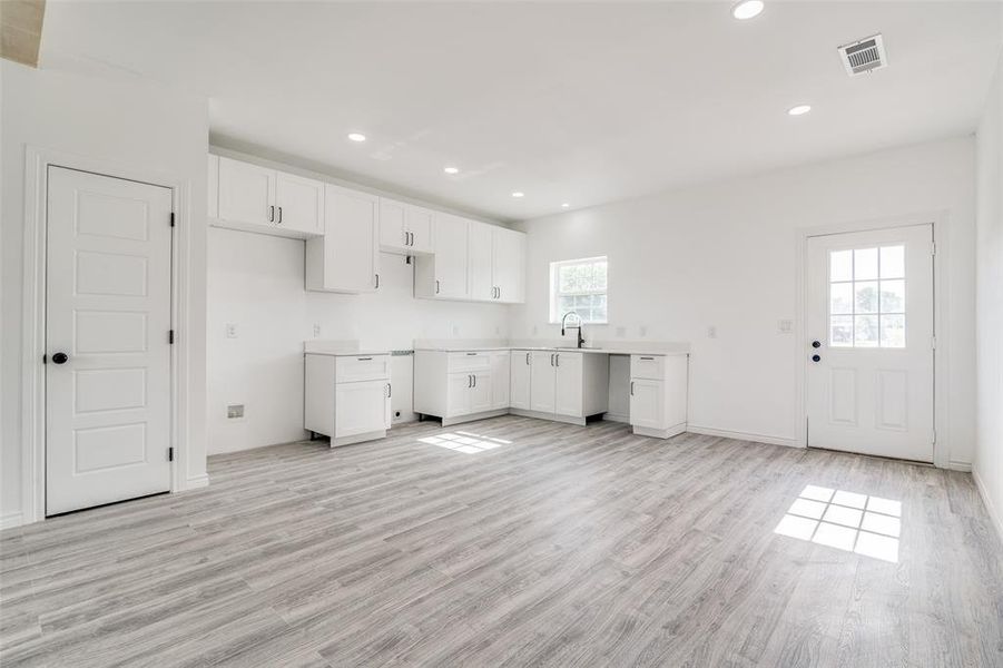 Kitchen with white cabinets, light wood-type flooring, and sink