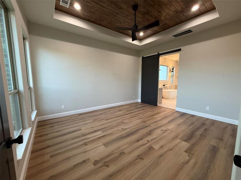 Unfurnished bedroom with a raised ceiling, wooden ceiling, wood finished floors, recessed lighting, and ensuite bath Unfurnished bedroom with a raised ceiling, wooden ceiling, wood finished floors, recessed lighting, and ensuite bath