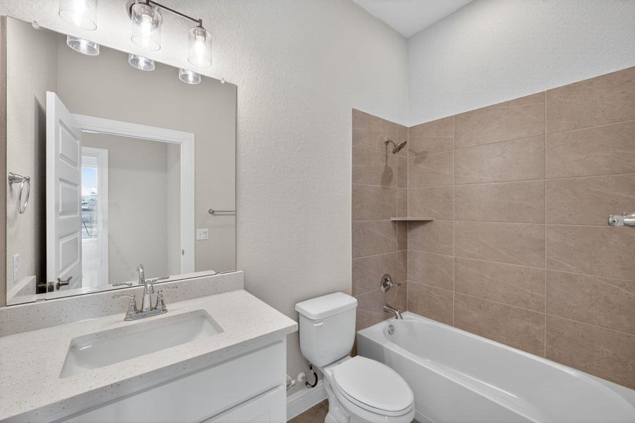 Bathroom featuring a textured wall, shower combination, and vanity Bathroom featuring a textured wall, shower combination, and vanity